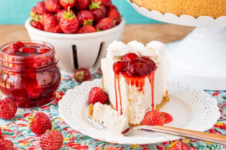 A slice of no bake cheesecake topped with strawberry sauce on a white plate.