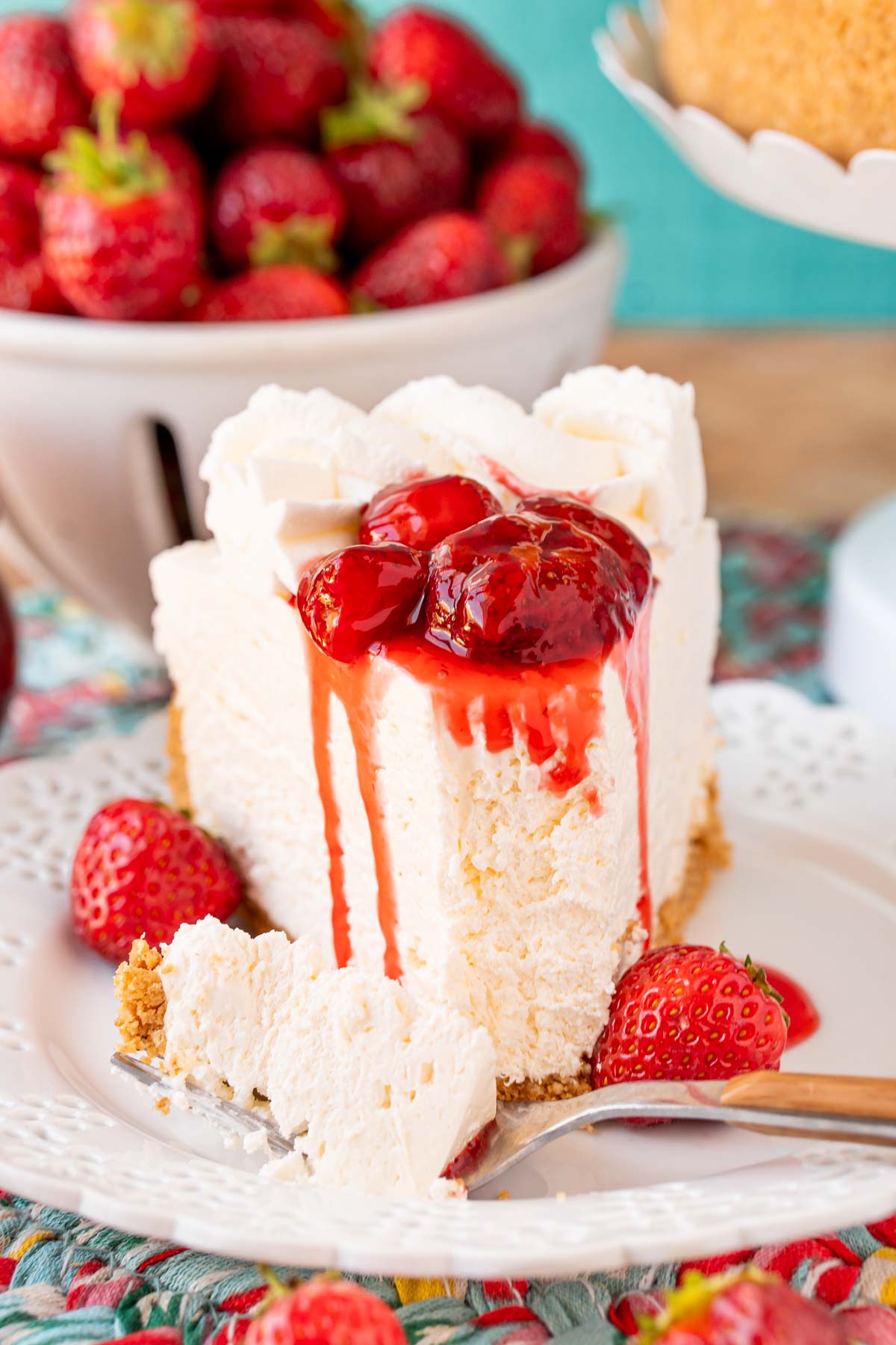 A slice of no bake cheesecake on a white plate topped with strawberry sauce.