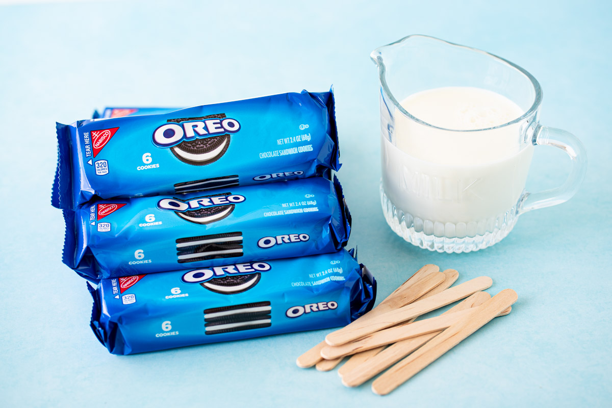 Ingredients to make Oreo popsicles on a blue surface.