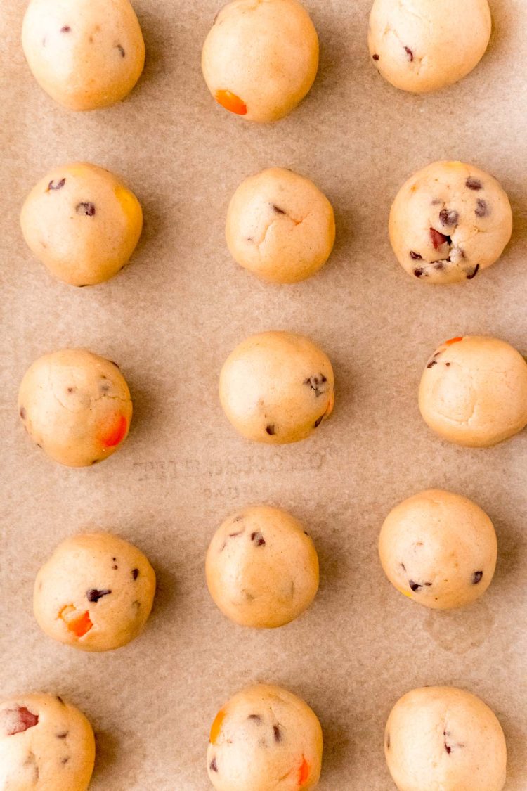 Peanut butter cookies dough truffle balls on a baking sheet ready to be dipping in chocolate.