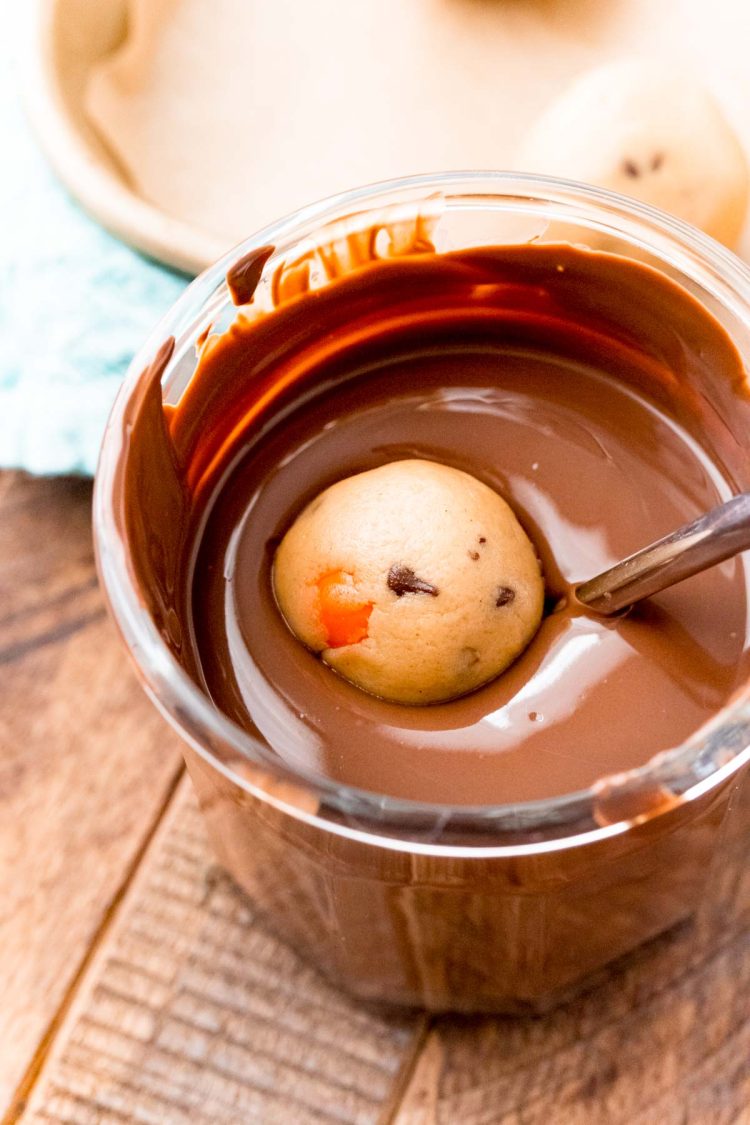 Peanut butter cookie dough truffles being dipped in melted chocolate.