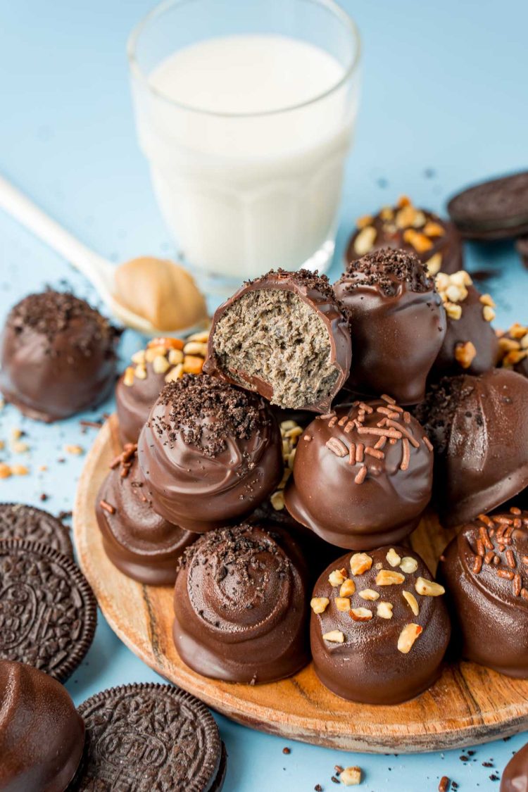 Close up of peanut butter oreo balls stacked on a wooden plate.