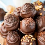 Close up of peanut butter oreo balls stacked on a wooden plate.