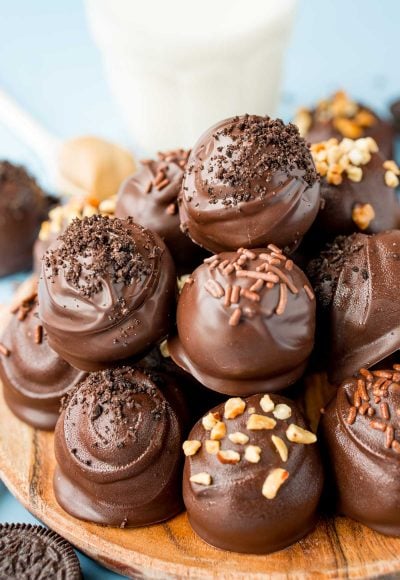 Close up of peanut butter oreo balls stacked on a wooden plate.