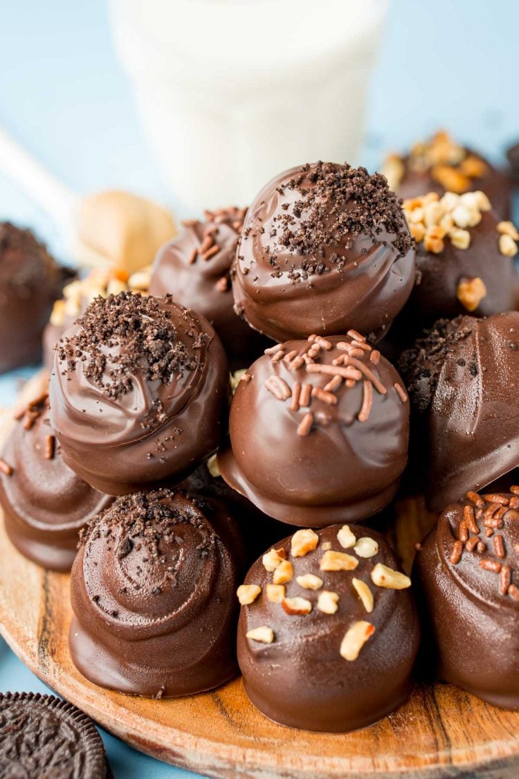 Close up of peanut butter oreo balls stacked on a wooden plate.