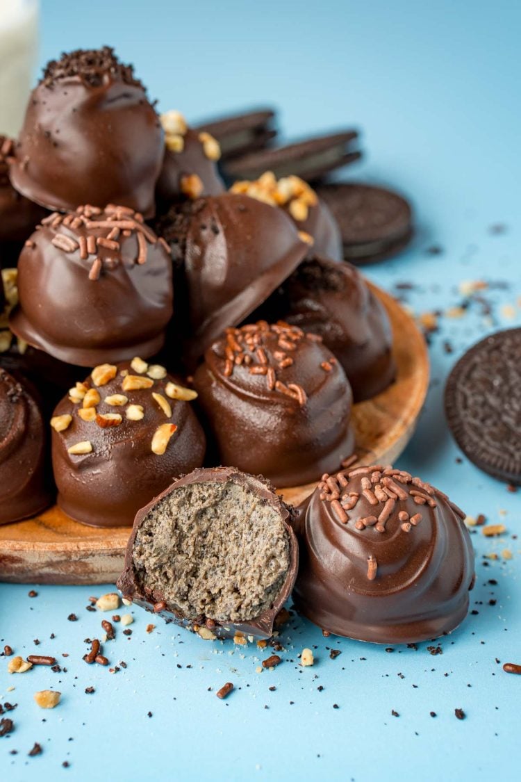 Peanut Butter Oreo Balls on a wooden plate on a blue surface.