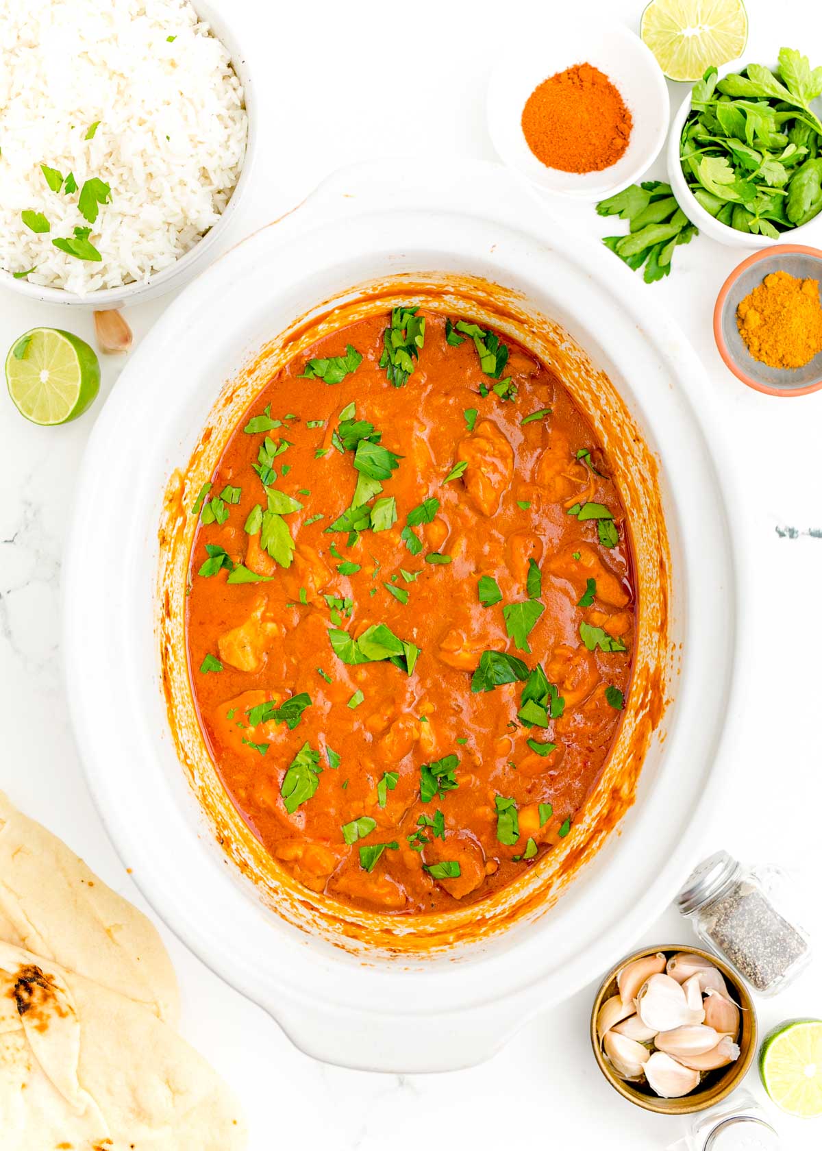 Overhead photo of a white crockpot filled with butter chicken.