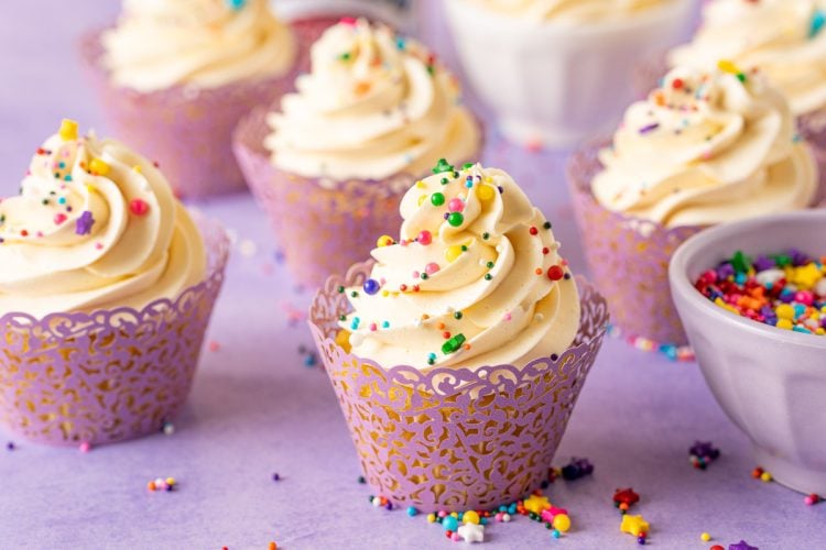 A cupcake topped with Russian buttercream on a purple surface.