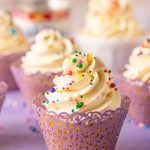 A cupcake topped with Russian buttercream on a purple surface.