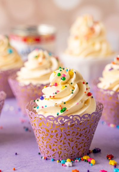 A cupcake topped with Russian buttercream on a purple surface.