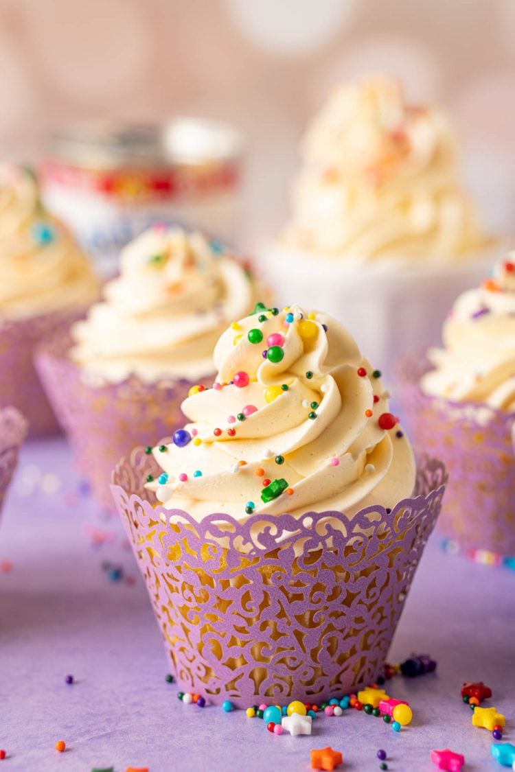 A cupcake topped with Russian buttercream on a purple surface.