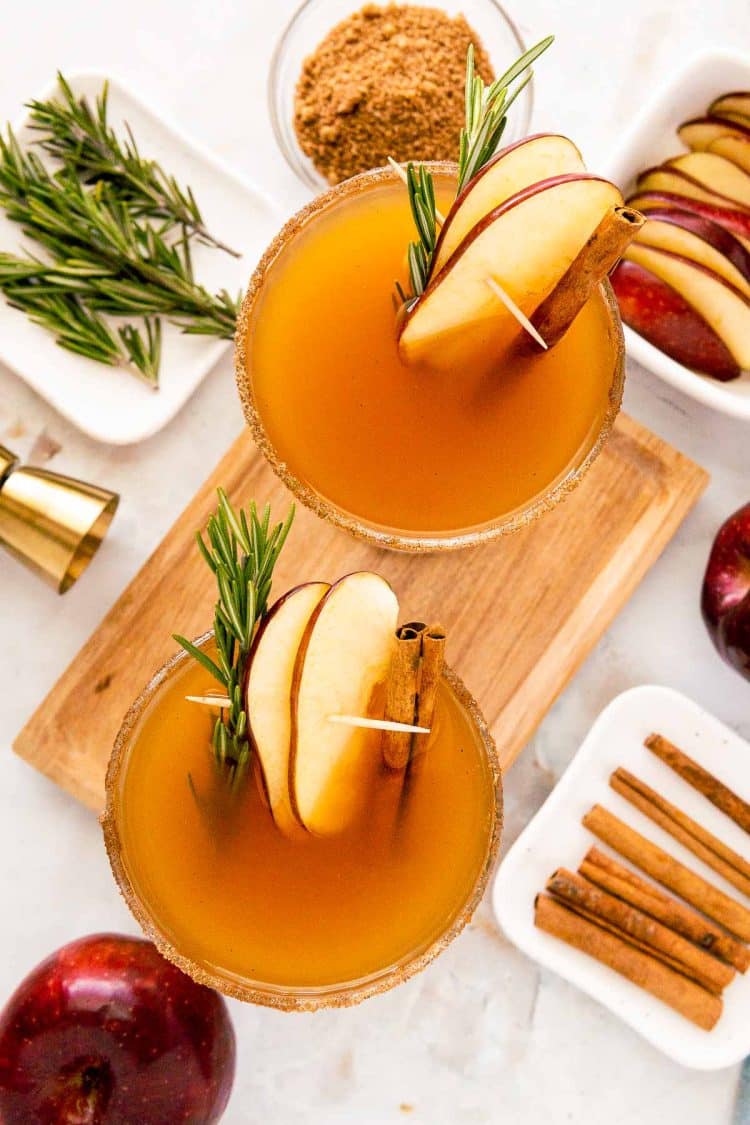 Overhead photo of two coupe glasses filled with apple cider bourbon cocktails.