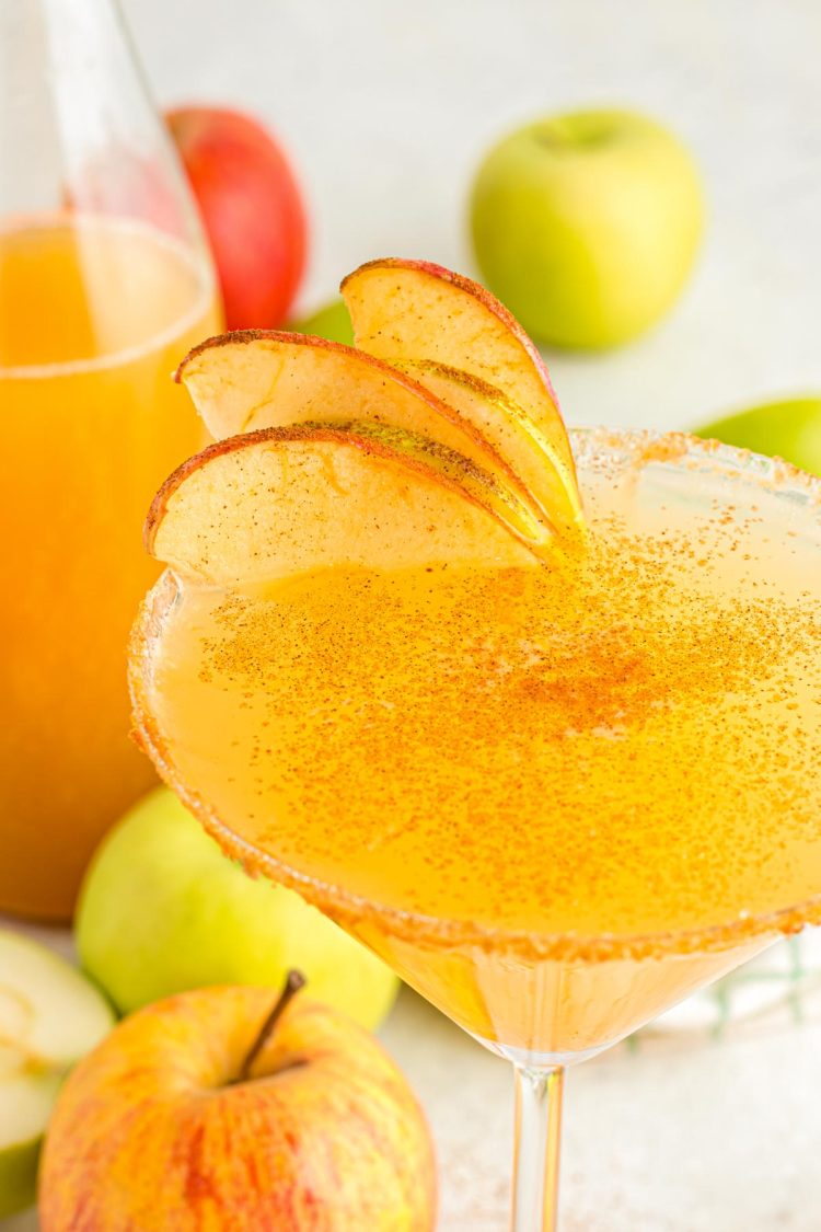 A close up of a martini glass with an apple martini in it.