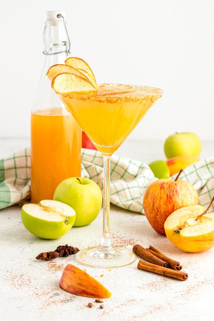 A martini glass filled with an apple cider martini on a white table.