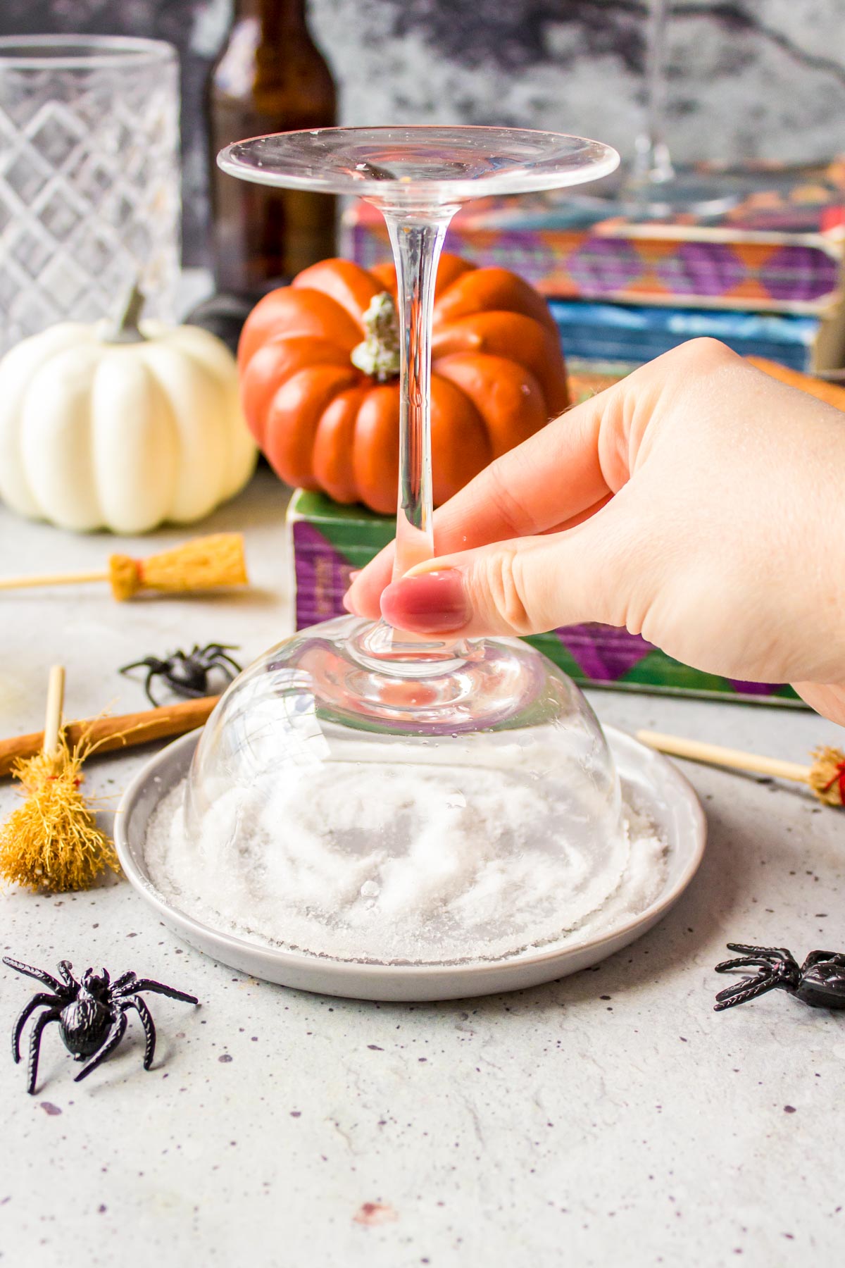 A coupe glass being dipped in a small plate filled with sugar to line the rim.