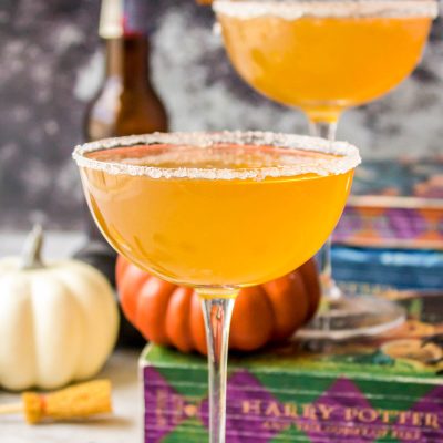 Butterbeer cocktails in coupe glasses with Harry Potter books in the background.