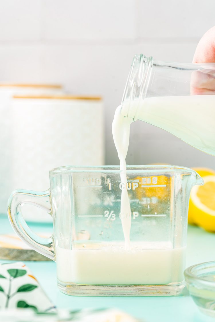 Milk being poured into a glass measuring cup.