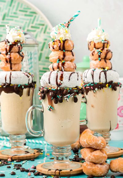 Three coffee milkshakes topped with donuts.