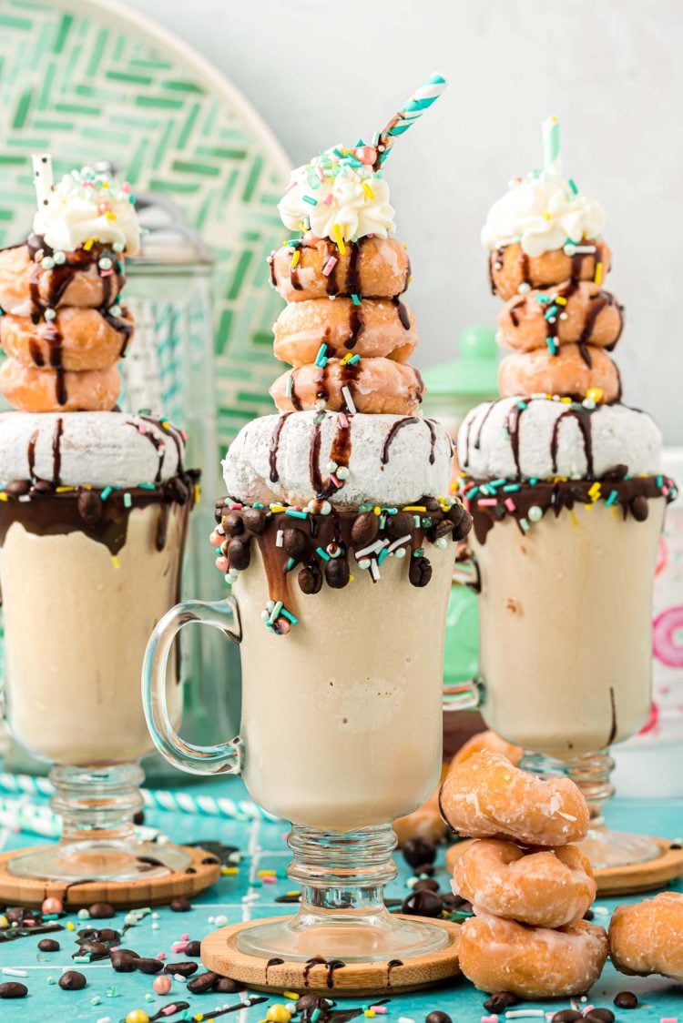 Three coffee milkshakes topped with donuts.