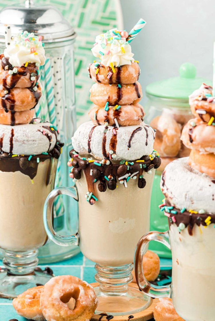 Three coffee milkshakes topped with donuts.