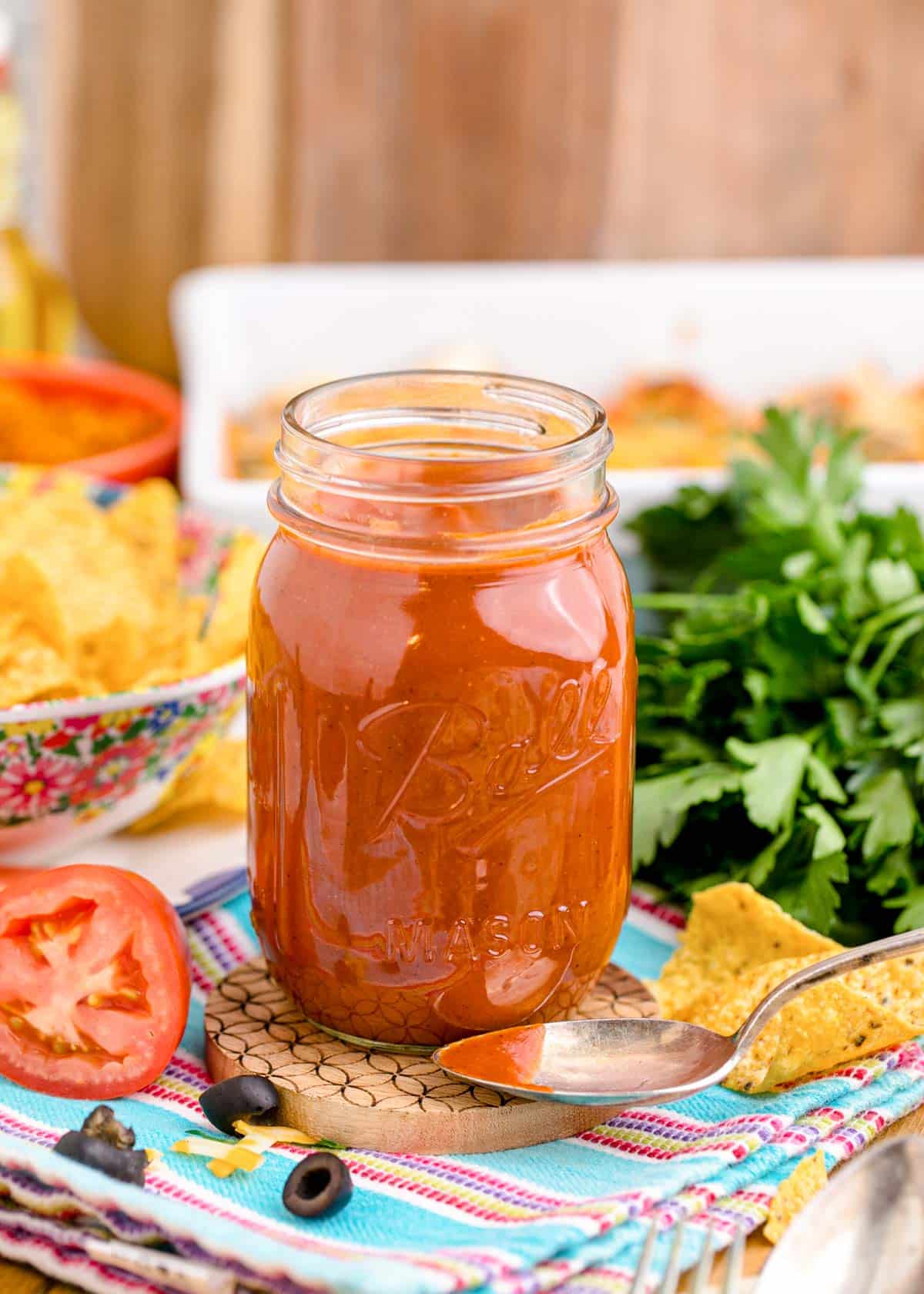 A jar of homemade enchilada sauce on a table.
