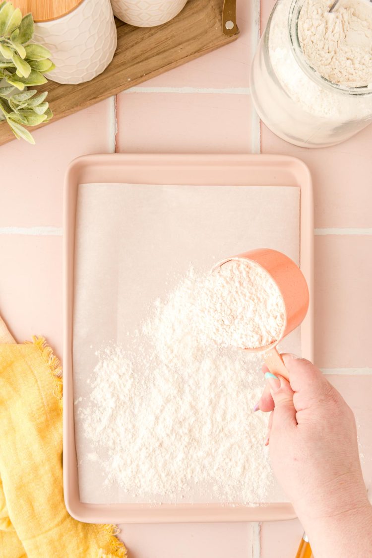 Flour being spread on a baking pan to be heat treated in the oven.