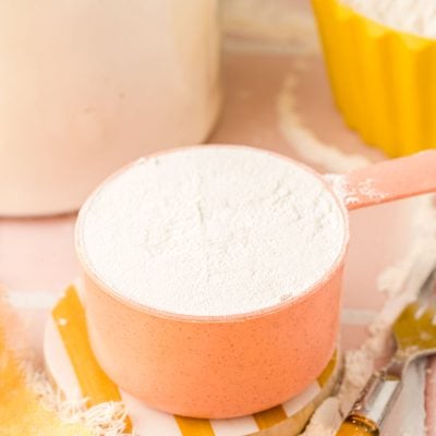a peach colored measuring cup filled with flour.