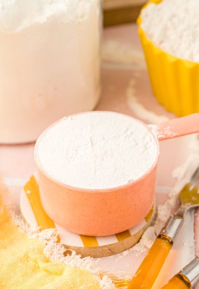 a peach colored measuring cup filled with flour.