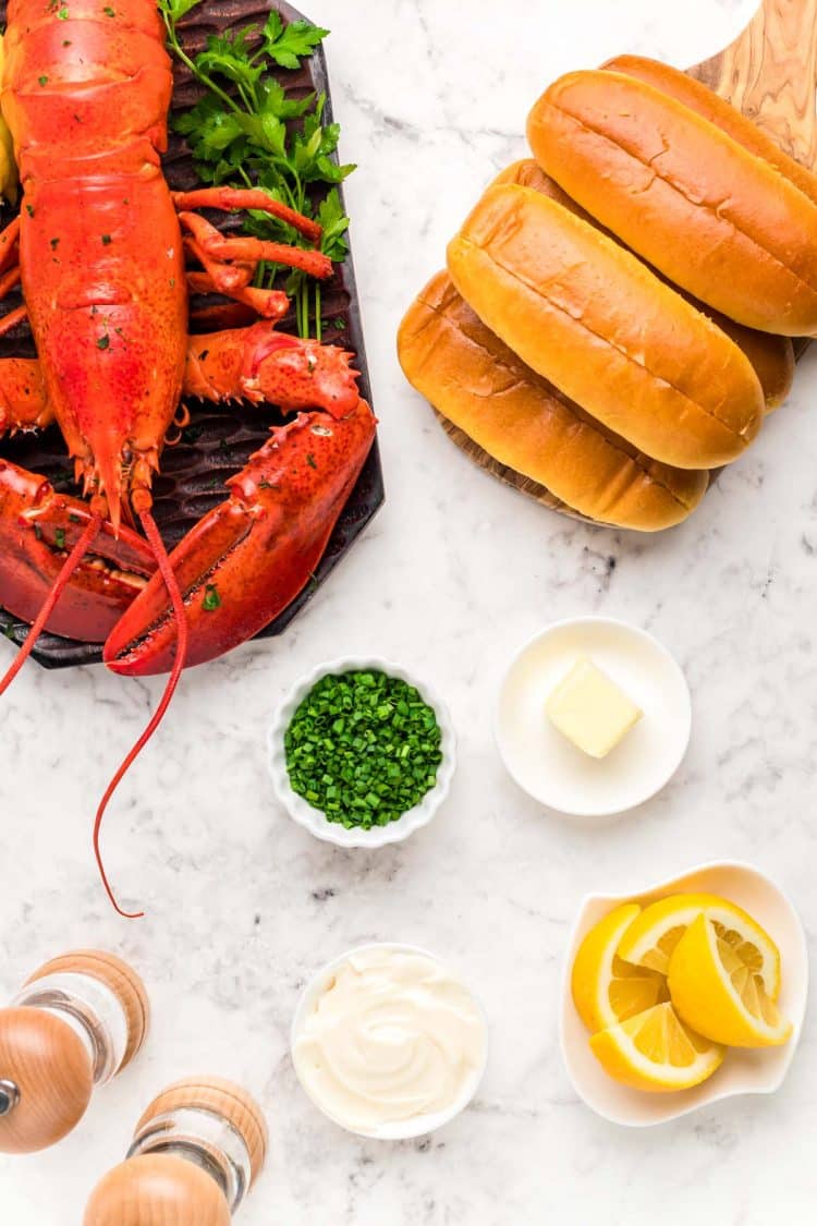 Ingredients to make a lobster roll on a marble surface.