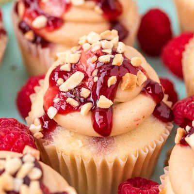 Close up of peanut butter and jelly cupcakes clustered together on a blue surface.