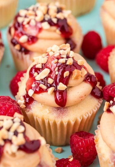 Close up of peanut butter and jelly cupcakes clustered together on a blue surface.