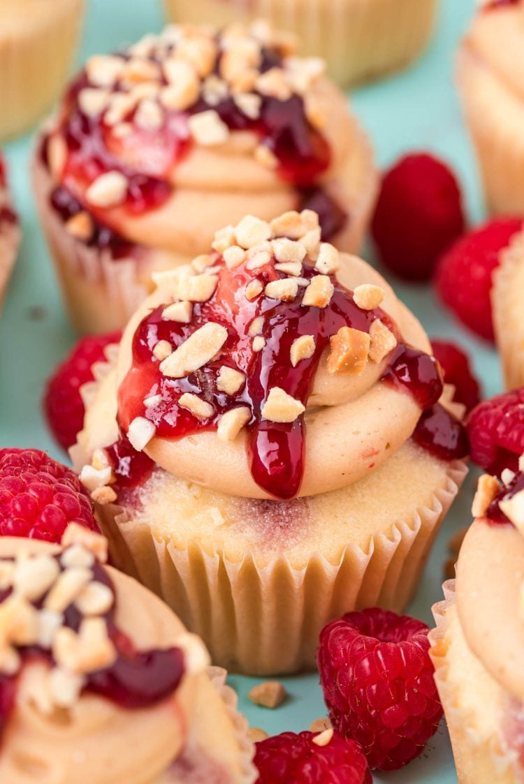 Close up of peanut butter and jelly cupcakes clustered together on a blue surface.