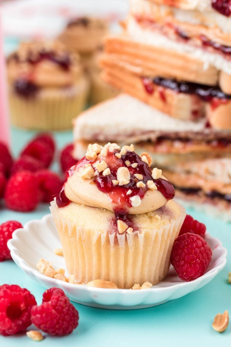 A peanut butter and jelly cupcake on a white plate on a blue surface.