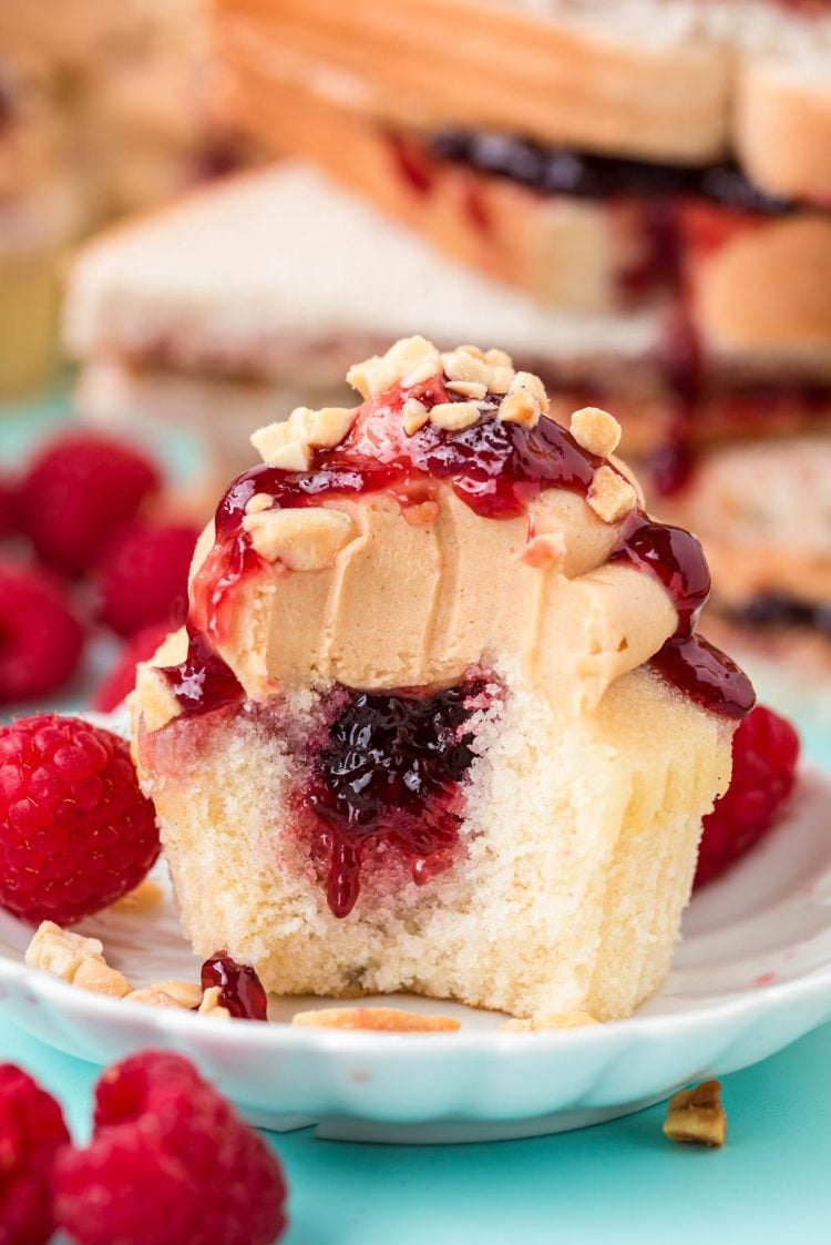 Peanut butter and jelly cupcakes with a bite taken out of it revealing the center of the cupcake.