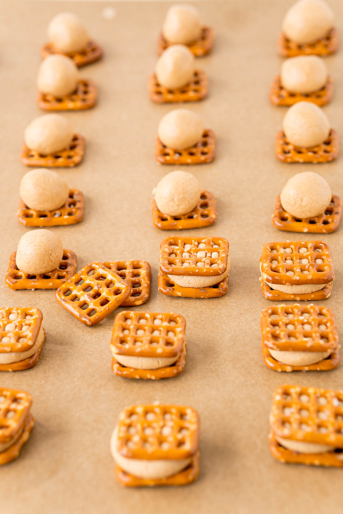 Peanut butter pretzel bites being made on a parchment lined baking sheet.