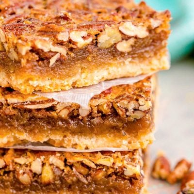 Close up photo of a stack of three pecan pie bars.