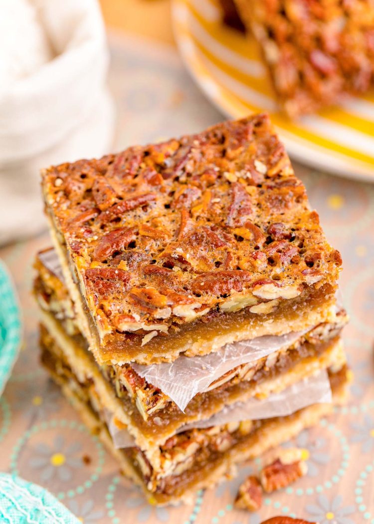 A stack of three pecan bars on parchment paper.