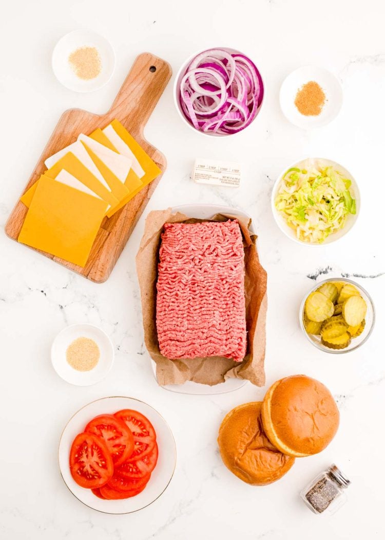 Ingredients to make homemade smash burgers prepped on a marble surface.