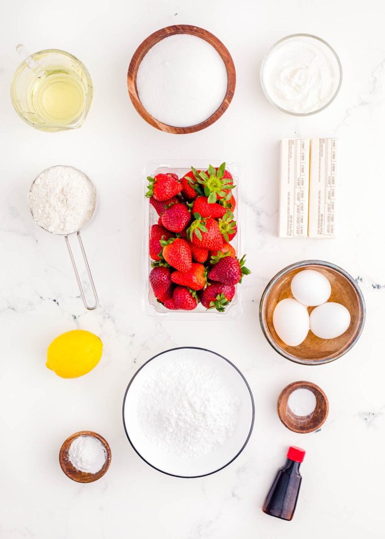 Ingredients to make strawberry sheet cake on a marble surface.