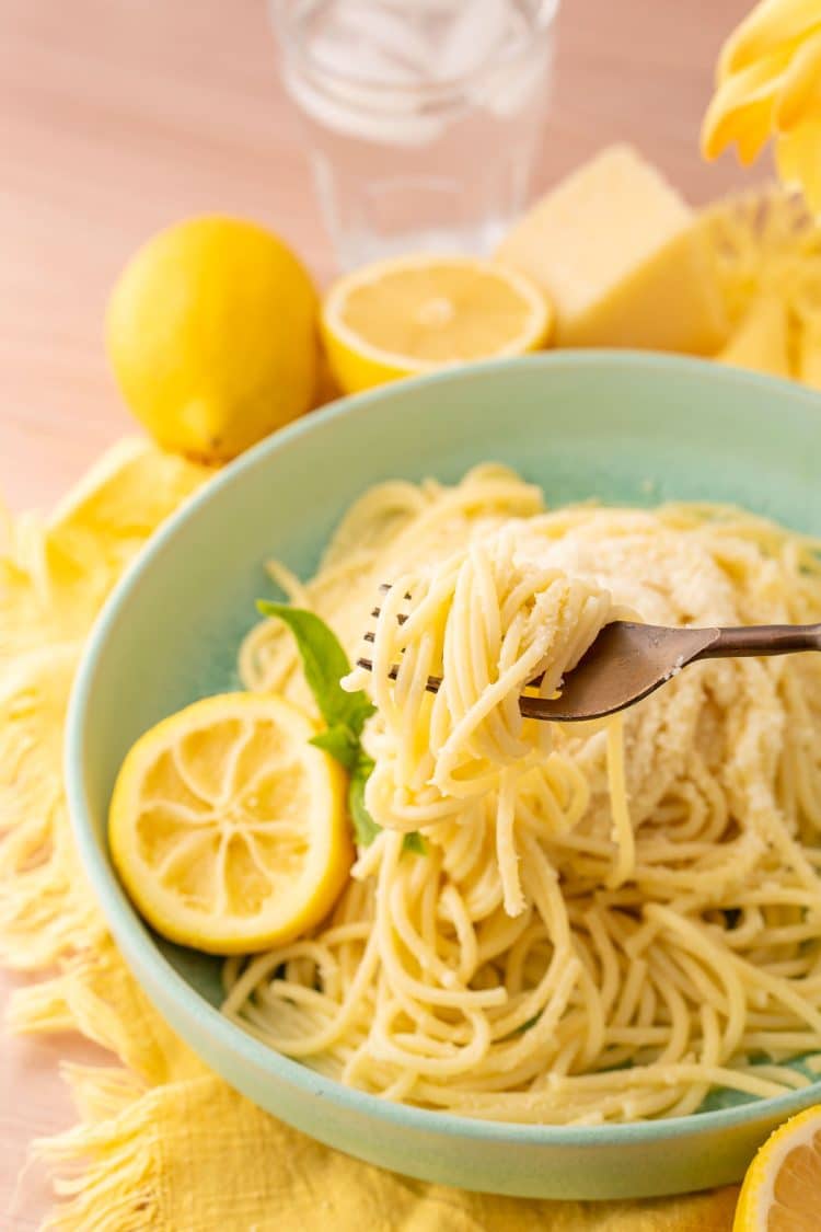 A fork pulling a bite of tiktok lemon pasta our of a mint green bowl.