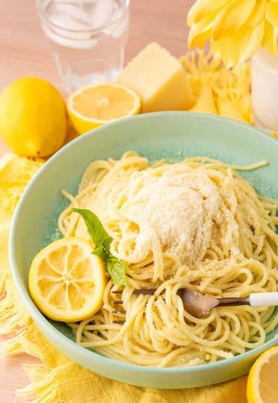 A green bowl filled with spaghetti limone on a yellow napkin.