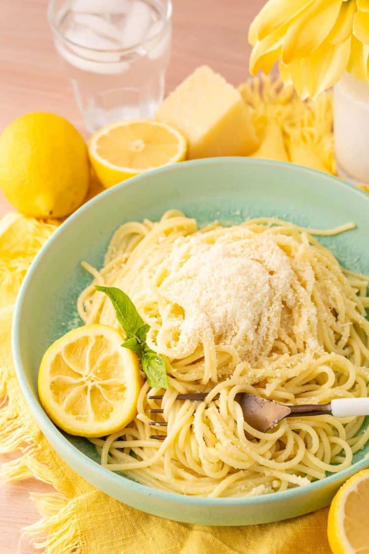 A green bowl filled with spaghetti limone on a yellow napkin.