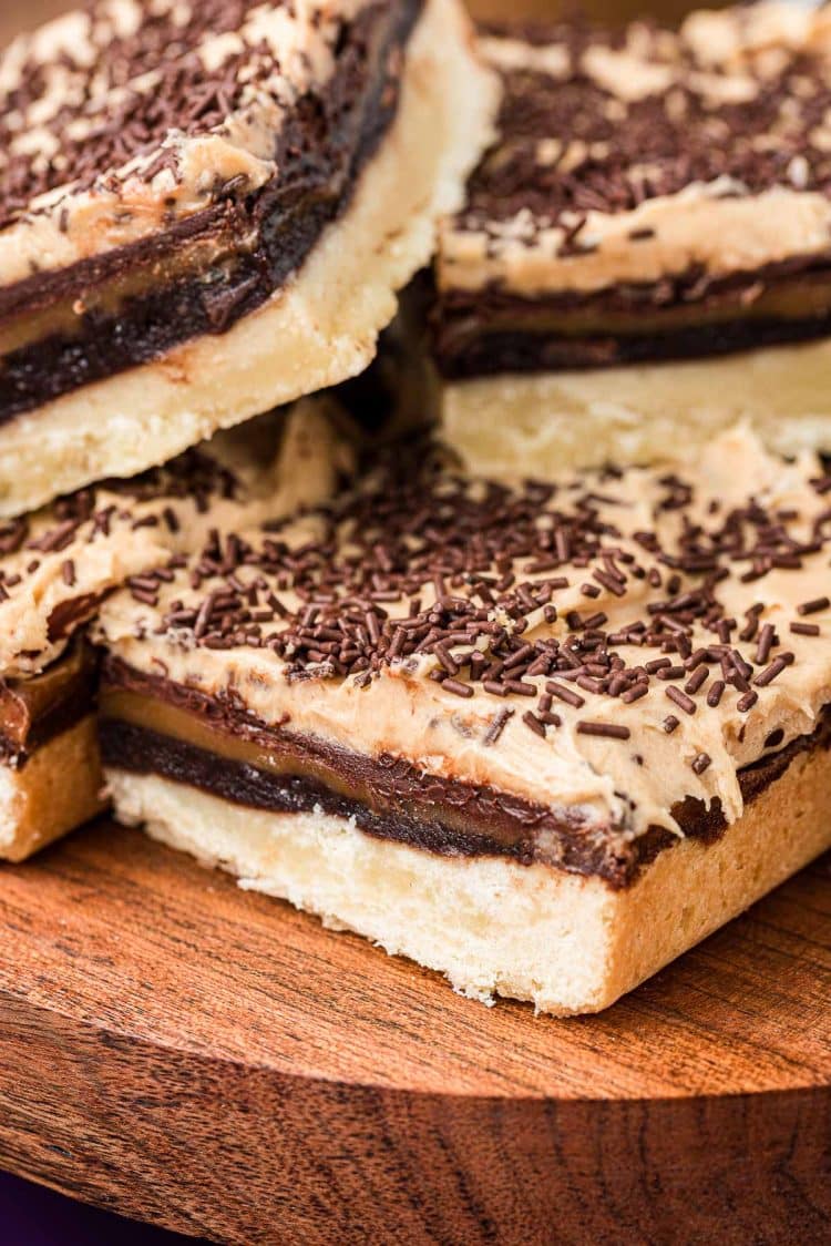 A pile of billionaire bars stacked on a wooden plate.