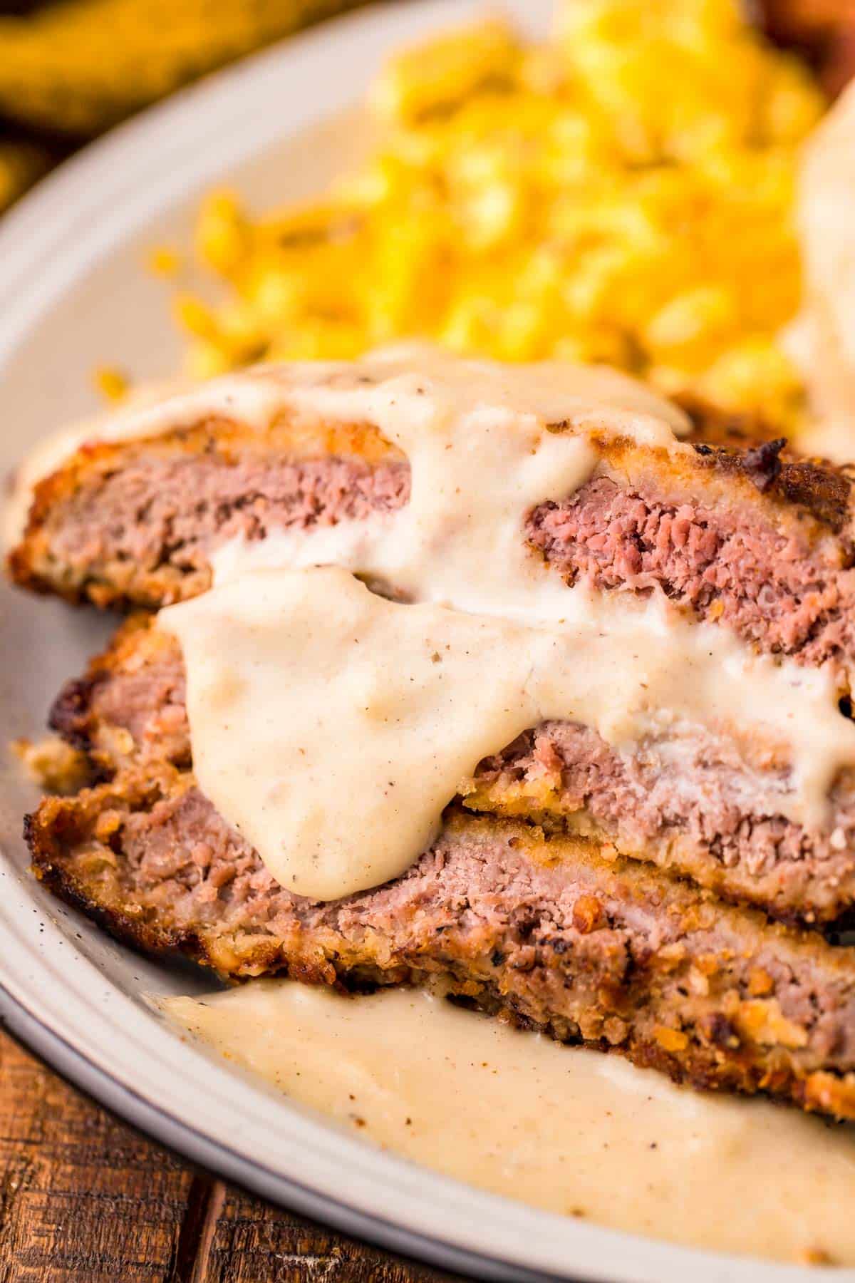 Sliced country fried steak on a plate topped with sawmill gravy.