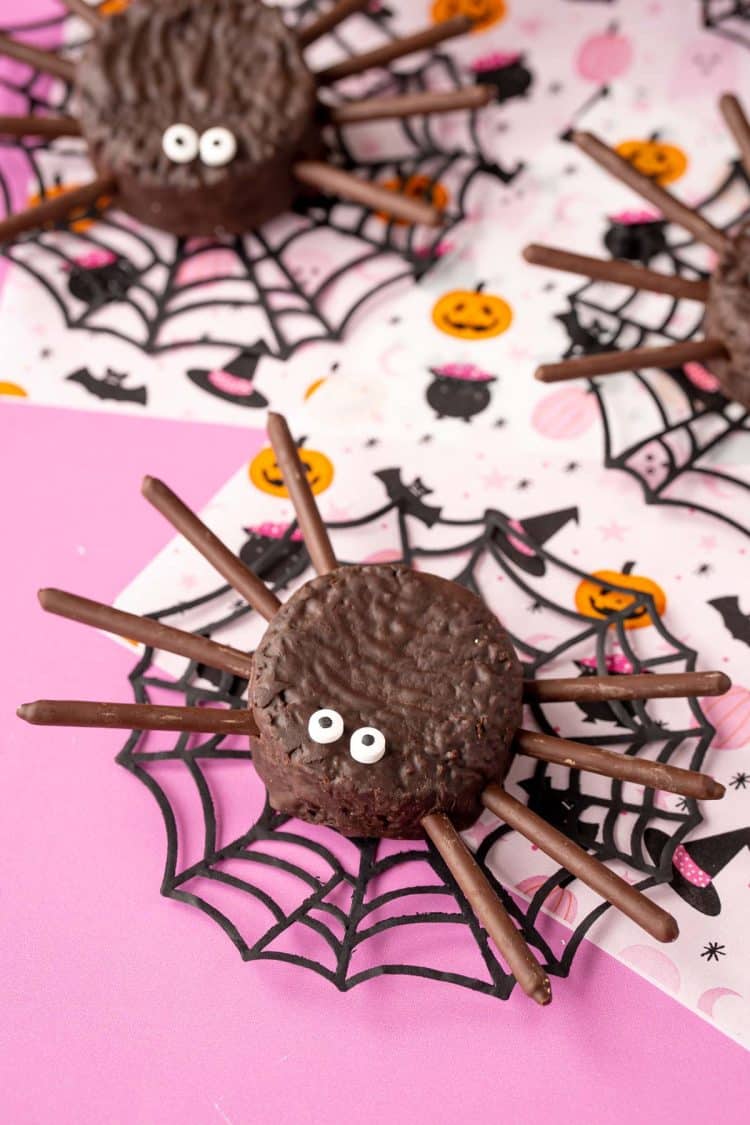 Close up photo of spider cakes on a pink surface.