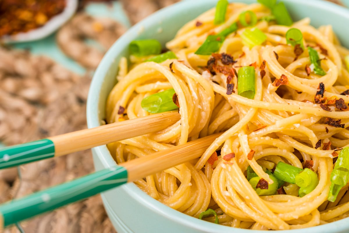 Chopsticks in a blue bowl of garlic noodles.