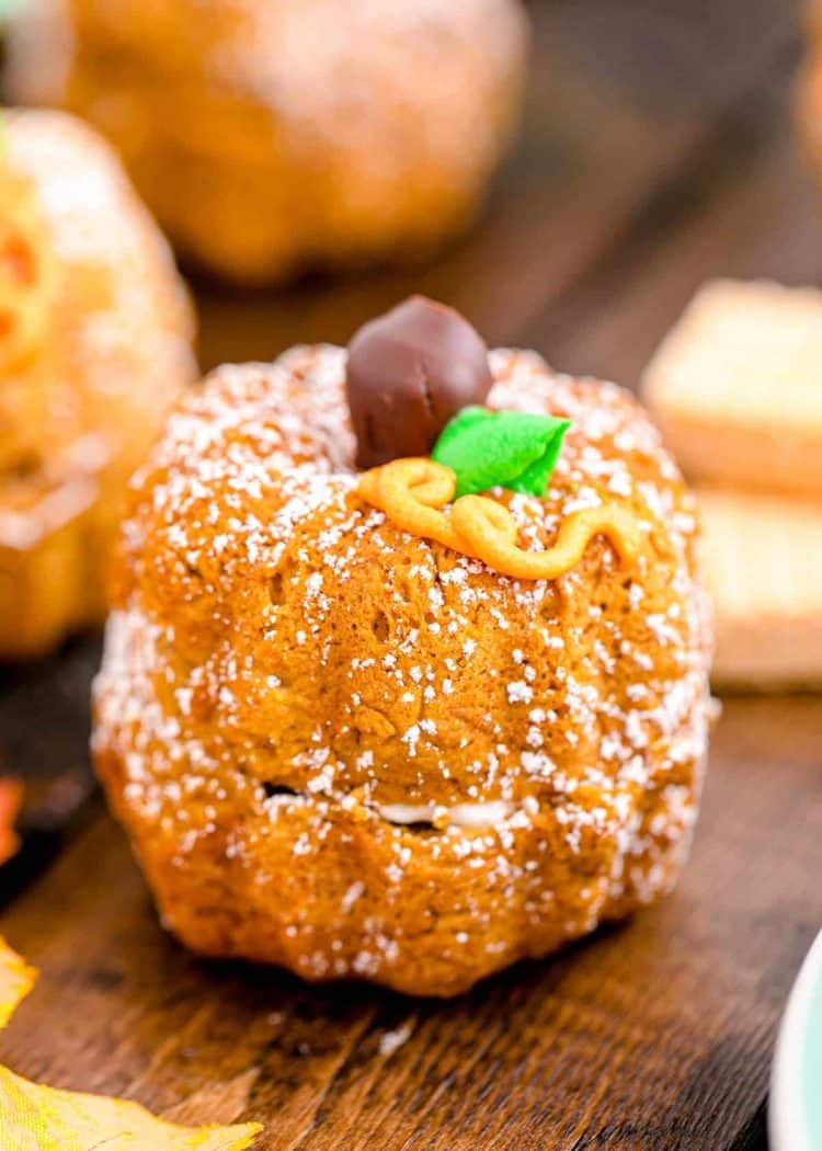 A mini pumpkin bundt cake shaped to look like a pumpkin on a wooden table.