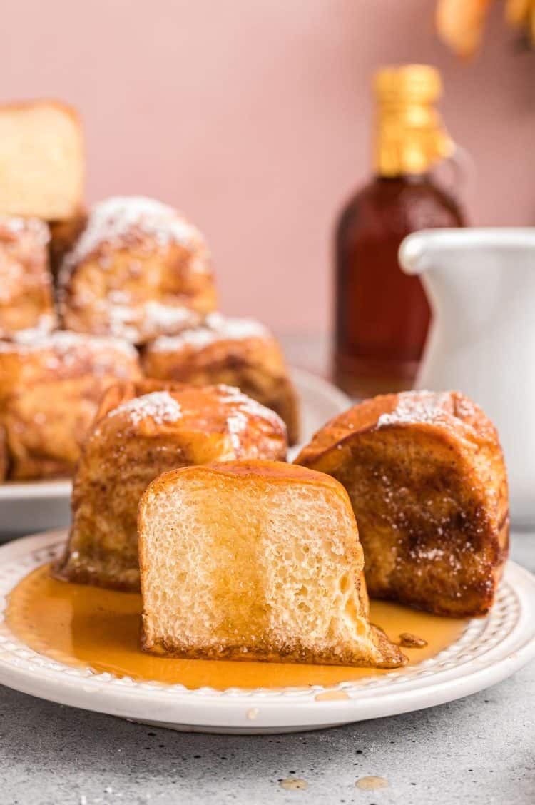 Hawaiian Roll French toast on a white plate, the front one has been sliced in half.