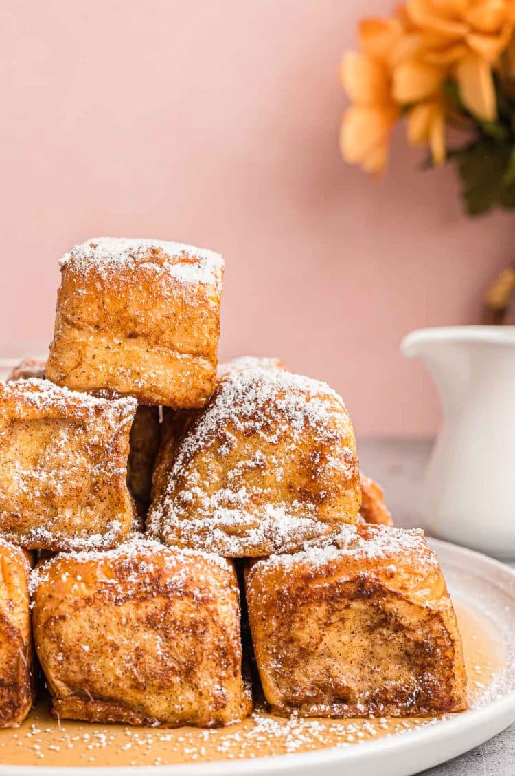 French toast sliders piled on a plate topped with powdered sugar.