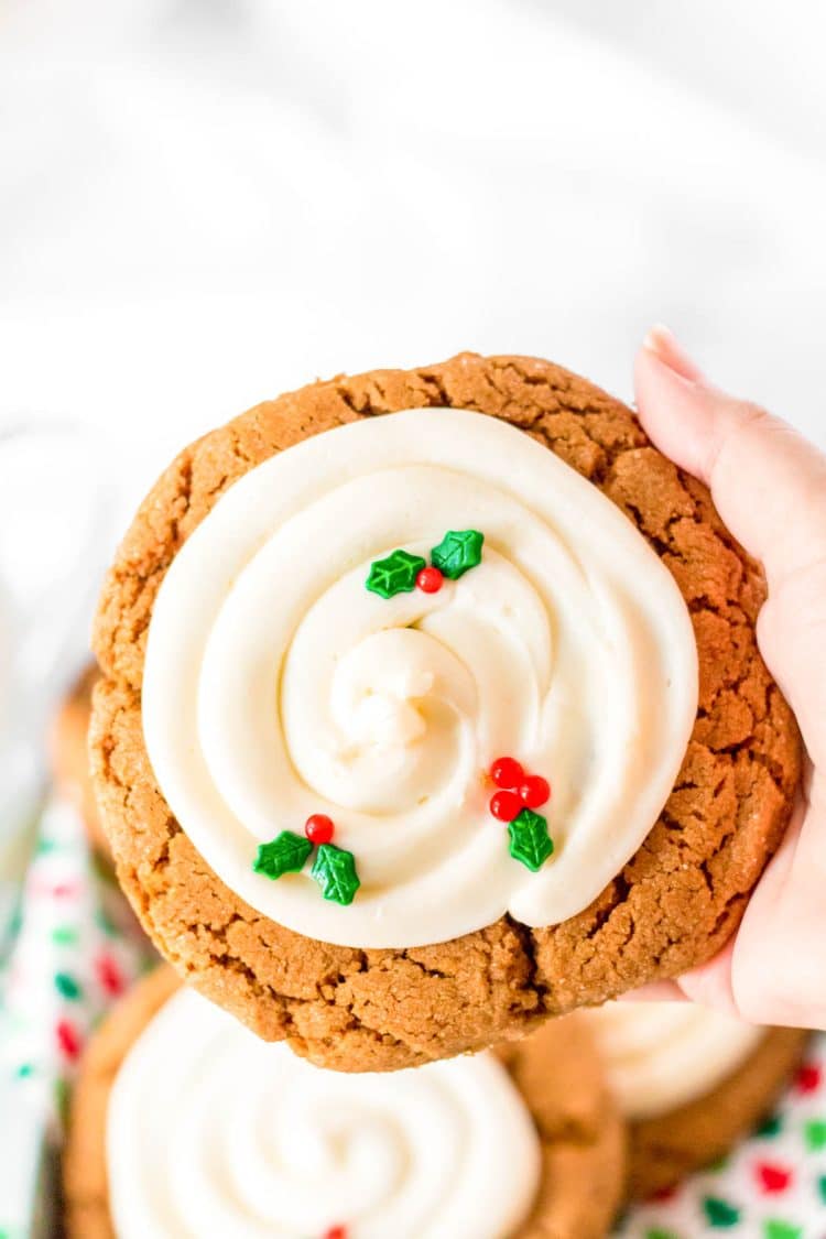 A woman's hand holding a giant gingerbread cookies with frosting.